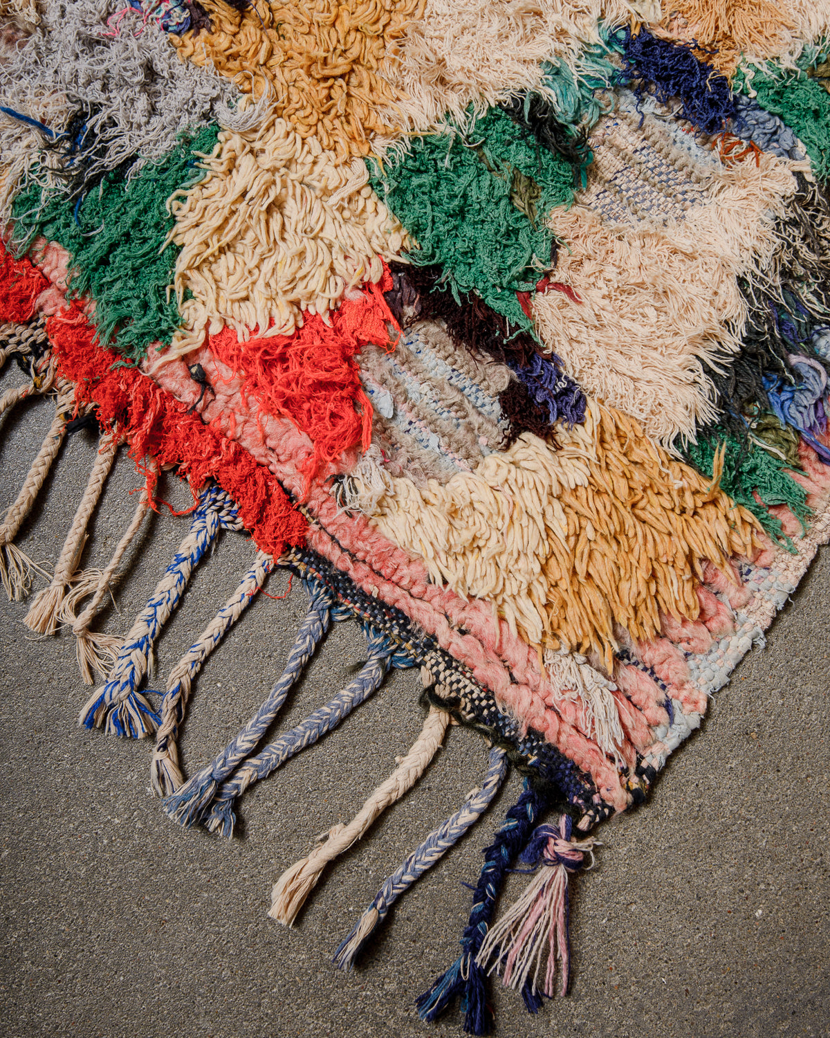 Multicolored woven rug with tassels on a textured surface